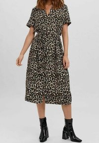 Leopardmönstrad midiklänning med korta ärmar, figursydd midja och en lös silhuett. Matchas med svarta ankelskor.