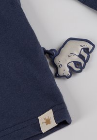 Marinefarbener Baumwoll-T-Shirt mit einem Eisbär-Applikation an der Ärmeln und einem beigen Stoffetikett mit einem Spritzdesign. Weicher Stoff, lässige Passform.