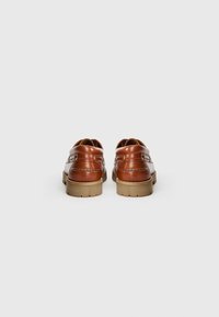 Brown leather shoes with a rounded toe, stitched detailing, and a light-colored rubber sole. Features a low profile and smooth texture.