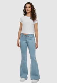 Lichtblauwe flared jeans van denim, met een hoge taille en vijf-pocket ontwerp, gedragen met een effen witte fitted t-shirt.