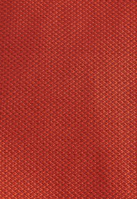 Tissu en maille rouge présentant un motif en losange. La texture est légèrement surélevée, offrant une qualité respirante et légère.