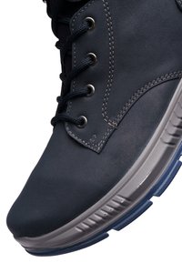 Dunkelblauer Lederschuh mit abgerundeter Spitze, kontrastierender Naht, Metallösen und einer strukturierten Gummisohle mit blauen Akzenten.