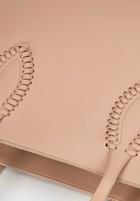 Beige leren handtas met gevlochten handvatten, een gladde textuur en versterkte stiksels. Heeft een gestructureerd ontwerp en een ruime binnenkant.