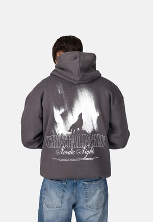 Dunkelgrauer, oversized Kapuzenpullover mit einem großen weißen Wolfs-Graphic und Text auf der Rückseite. Weicher Stoff mit lässiger Passform und Kordelzug-Kapuze.
