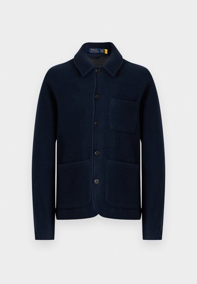 Chaqueta de lana azul marino con cuello tipo solapa, botones en el frente y dos bolsillos grandes. La textura parece suave y tejida con un acabado liso.