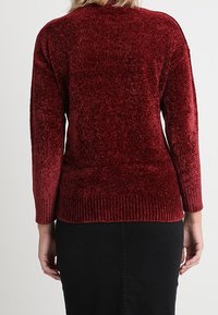 Karmesinroter, strukturierter Pullover mit einer weichen, flauschigen Oberfläche und gerippten Bündchen. Entworfen mit einem runderen Halsausschnitt und leicht übergroßem Schnitt.