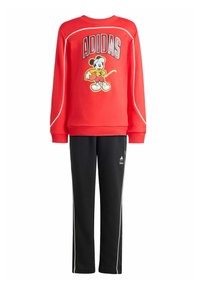 Czerwona bluza z kapturem z logo Adidas i grafiką Myszki Miki; zestawiona z czarnymi spodniami z białymi paskami po bokach i logo Adidas.