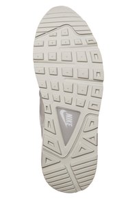 Nike sneaker outsole in light gray with a textured rubber surface, featuring a triangular cutout and various patterned lugs for grip.