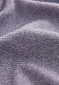 Lágy, tompított levendula színű textil. Az anyag finom kötött mintázattal rendelkezik, enyhe eltérésekkel és diszkrét színfoltokkal.