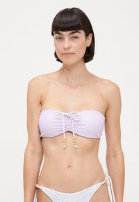 Bikini set featuring a lilac bandeau top with ruching and front tie detail, accented with wooden beads; matching patterned side-tie bikini bottom.