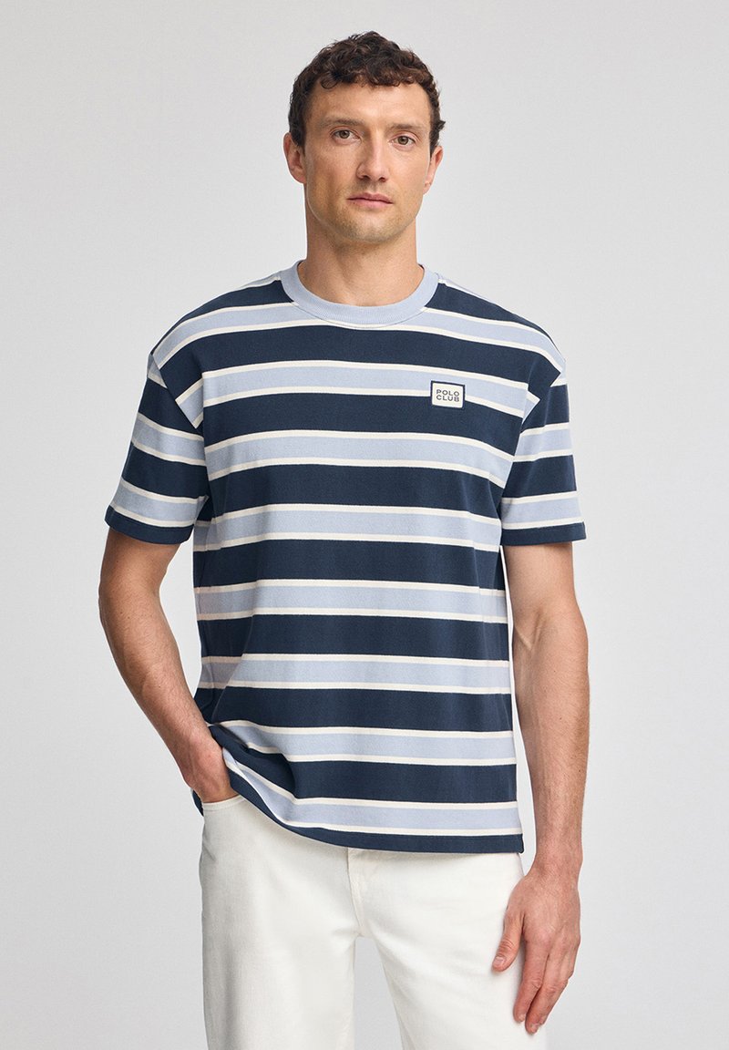 Randig bomull T-shirt i marinblått och ljusblått, rund halsringning, korta ärmar, och en liten rektangulär logotyp på bröstet.