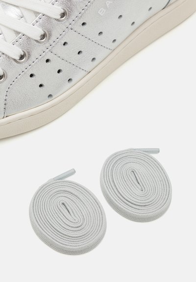 Silver leather sneaker with white laces, perforated detailing, and a rubber sole. Includes two round light gray shoelaces.