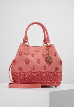 Borsa rosa con texture decorata e charm dorato decorativo, con doppi manici e tracolla staccabile su superficie bianca.