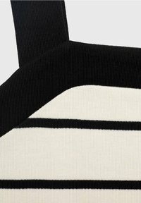 Tessuto a strisce nere e crema con texture a costine; presenta larghe spalline nere e un'area liscia crema con sottili linee nere.