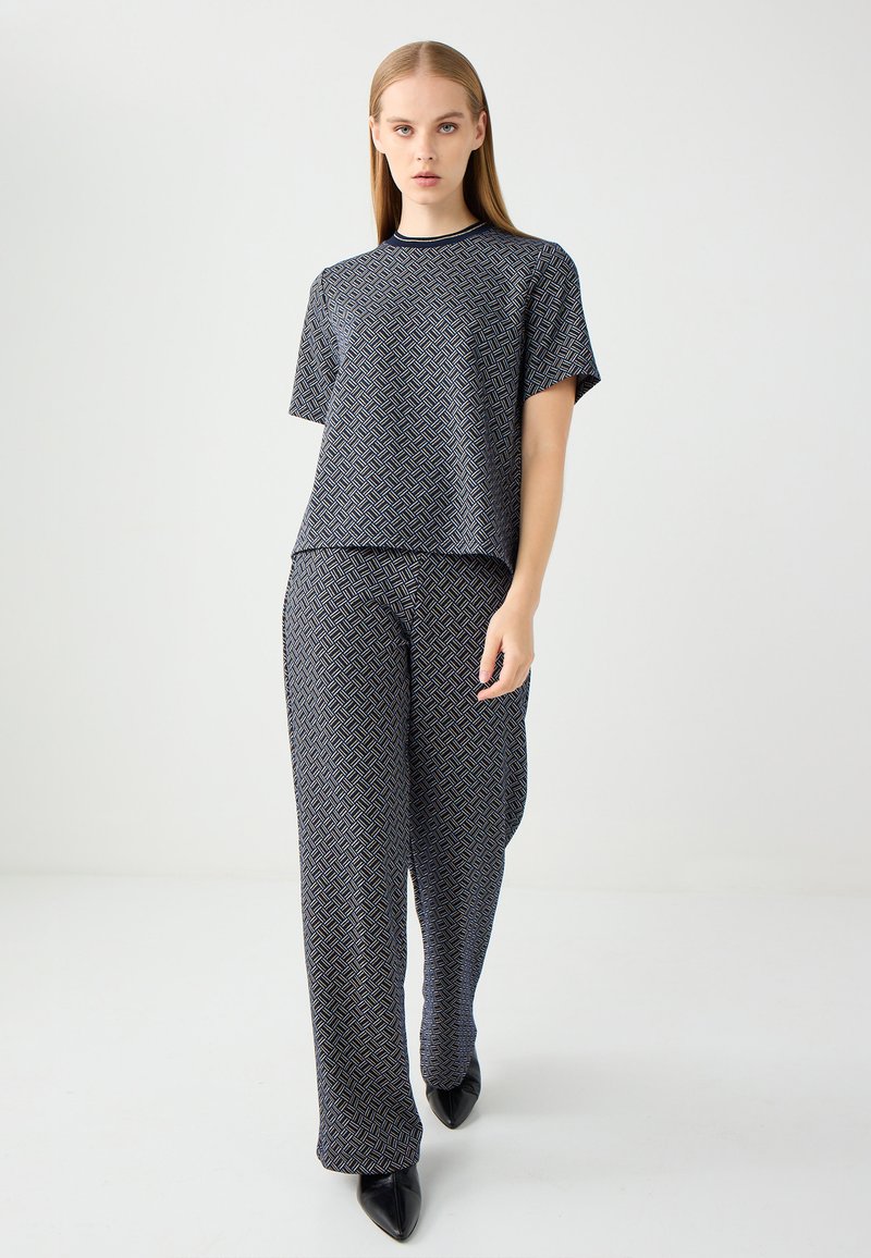 Blauw en zwart gestreepte twee-delige outfit met een short-sleeve top en losvallende broek, gemaakt van een gladde stof met een geometrisch ontwerp.