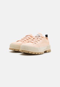 Scarpe da ginnastica rosa chiaro con una parte superiore in tessuto testurizzato, dotate di una suola beige spessa, lacci tondi e un tassello nero sul tallone.