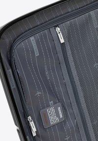 Gray travel bag interior with mesh pockets, zigzag patterns, and branded label. Features two zippered compartments for organized storage.