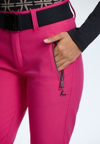 Pink fitted pants with a smooth texture, featuring a zippered pocket and a black belt. The design includes a sleek silhouette and minimal hardware.