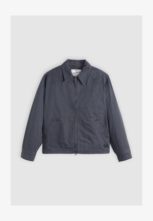 Veste gris foncé avec zip à l'avant, col pointu, deux poches latérales et détails de couture subtils. Fabriquée en tissu lisse.