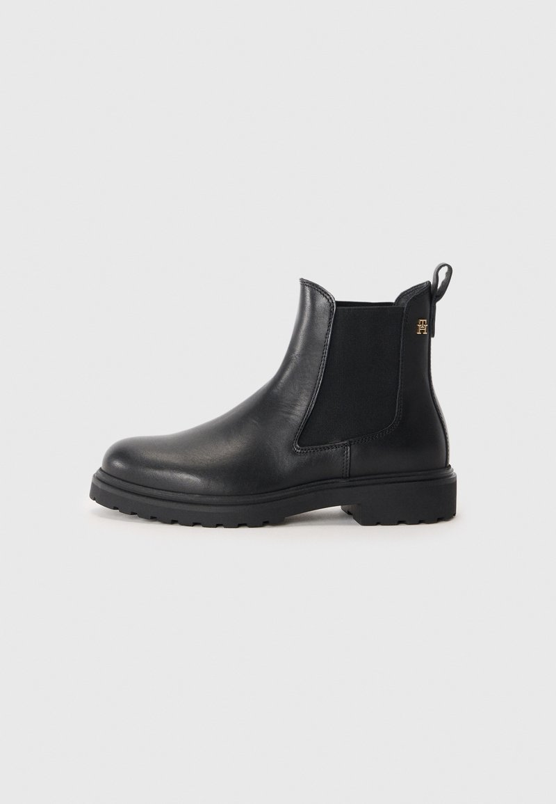 Botte Chelsea en cuir noir avec panneau latéral élastique, languette de tirage, semelle crantée et petit logo doré sur le côté arrière supérieur.