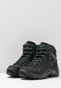 Mid-Cut-Wanderschuhe aus dunkelgrünem Wildleder mit türkisfarbigen Akzenten, verstärkten Ösen, gepolsterten Kragen und strukturierten schwarzen Gummisohlen.