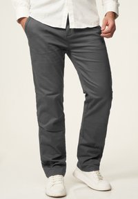 Gray cotton chinos with a straight fit, featuring back pockets and a smooth texture, paired with white sneakers on a light background.