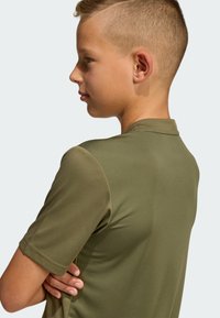 Olivovozelené polo tričko s krátkym rukávom, rebrovanou textúrou, plochým golierom a jemným leskom. Na chrbte má nenápadné logo.