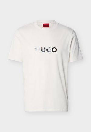 T-shirt blanc à manches courtes et col rond avec le logo "HUGO" réfléchissant centré sur la poitrine.
