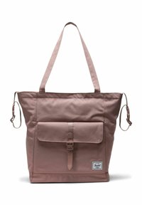 Sac tote mauve avec de longues bandoulières, poche avant à rabat avec boucle et sangles latérales ajustables, arborant une petite étiquette de marque.