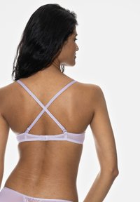 Lilac bralette with adjustable crossover straps, smooth texture, hook closure at the back, and minimalistic design.