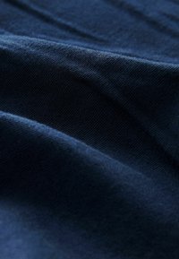 Laivansininen kangas, jossa on sileä pinta, esittää pehmeitä taitoksia ja hienovaraisia vaihteluita. Materiaali näyttää hengittävältä ja siinä on tasainen kudonta.