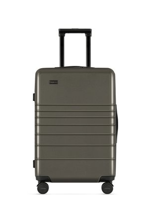 Hard-shell suitcase in olive green with a textured surface, vertical grooves, retractable handle, and four black wheels for mobility.