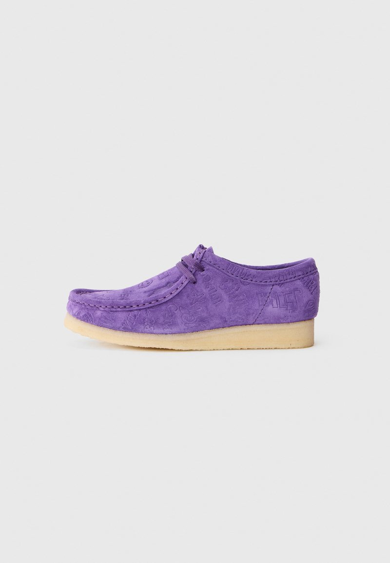 Chaussure en daim violet avec un bout arrondi, des motifs en relief subtils et une semelle en caoutchouc beige clair. Comprend des lacets pour un ajustement sécurisé.