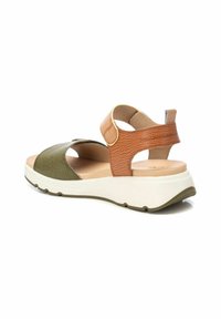 Sandalia bicolor que presenta cuero de color verde oliva y marrón con un acabado texturizado. Correa ajustable y suela de plataforma blanca con un sutil relieve.