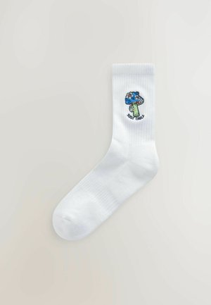 Hvide bomuldsstrømper med et farverigt svampedesign med blå hat og grøn stilk, ledsaget af teksten "MUSH GROW." Ribbet tekstur ved toppen.