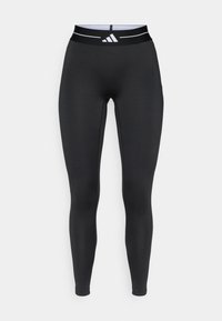 Leggings de sport noirs en matériau extensible, avec une taille haute ornée d'un accent à rayures blanches et du logo de la marque. Texture lisse.