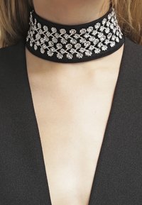  Černý náhrdelník s květinovým vzorem z čirých rhinestones, s texturovaným textilním podkladem, těsně obepíná krk a zvýrazňuje svůj zdobený design.