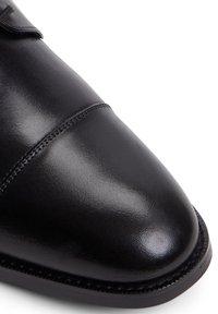 Chaussure habillée en cuir noir avec une finition satinée, bout rond, détails de couture subtils et semelle robuste.