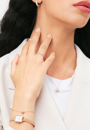 Rose gold jewelry, including hoop earrings, a textured ring, a bracelet with a charm, and a pendant with a round accent. Smooth finish.