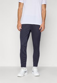 Navy athletic pants with a slim fit, made from lightweight material, featuring an elastic waistband and a small logo detail near the pocket.