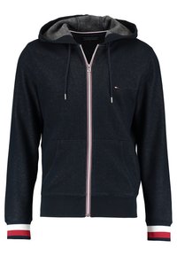 Sweat à capuche zippé bleu marine avec doublure grise à l'intérieur de la capuche, poches avant, cordons et poignets rayés rouges, blancs et bleus aux manches.