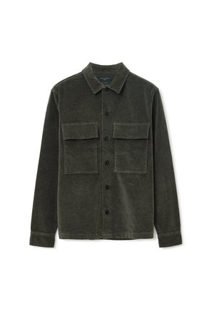 Dark green corduroy shirt jacket featuring a collar, two chest pockets, and button front closure with black buttons. Soft texture and structured shape.