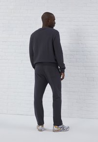 Dunkelgrauer Pullover und passende Jogginghose aus weichem Material. Der Pullover hat gerippte Bündchen und einen Saum; die Jogginghose verfügt über eine Gesäßtasche.