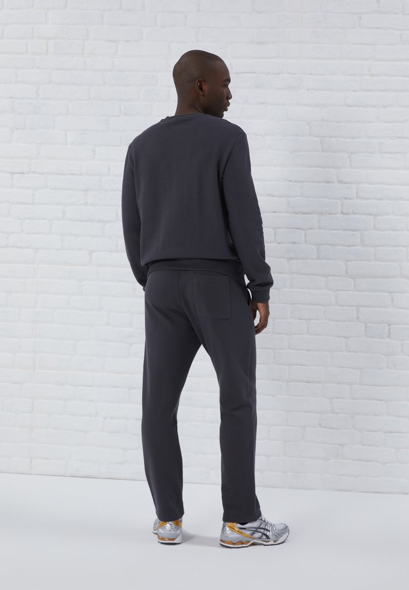Sweatshirt gris foncé et joggers assortis en tissu doux. Le sweatshirt a des poignets et un ourlet côtelés ; les joggers comportent une poche arrière.