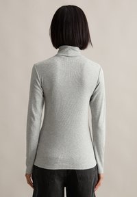 Grijs, lange mouwen turtleneck sweater met een ribbelstructuur, aansluitend ontwerp en een hoge kraag, gecombineerd met donkere, losse broek.