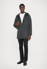Gray zip-up coat with a hood, made of soft material. Black trousers and shoes, plain white t-shirt underneath. No patterns or visible hardware.