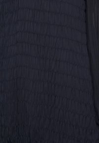Navy textured fabric with a crinkled design, featuring horizontal seams. Material appears lightweight, with a smooth and slightly shiny finish.