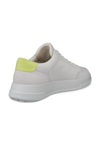 Białe skórzane sneakersy o teksturowanym wykończeniu, z jaskrawą żółtą zakładką na pięcie, białą gumową podeszwą i sznurowanym zapięciem.