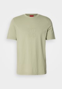 T-shirt vert clair à manches courtes avec col rond et logo "HUGO" brodé sur la poitrine.