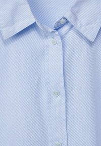 Ljusblå vävd skjorta med vertikala ränder, som har en klassisk krage, två knappar och ett mjukt, texturerat tyg.